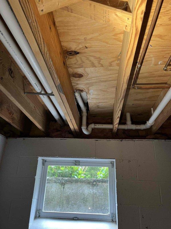 Completed plumbing membership inspection at the property, examining exposed PVC drainage lines in the basement utility area and under-sink plumbing fixtures. All visible pipes, P-trap configuration, and mounting brackets were inspected and found to be in proper working condition with no leaks or deficiencies noted.