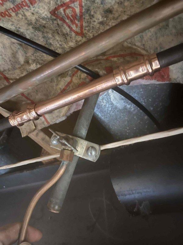 Completed return visit to finalize plumbing repair installation previously sold. Installed white PVC drainage piping system beneath subfloor with proper angular connections, elbow fittings, and directional changes secured to floor joists using plastic mounting straps. All pipe segments properly joined and clamped to wooden framing members to ensure stable, code-compliant installation. Documented completed work showing clean PVC drainage system with no visible leaks or defects, along with adjacent copper supply lines and mechanical components in crawl space area.