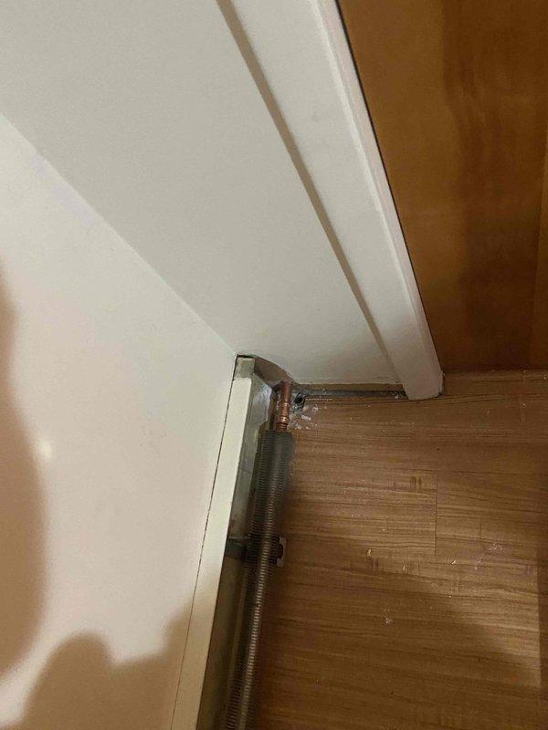 Completed boiler system installation with magnetic filter integration in residential space. Installed baseboard heating unit with copper piping connections along interior wall, ensuring proper hydraulic connections to existing boiler system. Magnetic filter was added to the heating system to capture debris and protect components from sediment buildup, extending system longevity and maintaining optimal efficiency. All piping connections were secured and tested for proper operation. System was pressurized, tested for leaks, and verified for proper heat distribution. Documentation captured showing completed baseboard installation and overall workspace configuration.