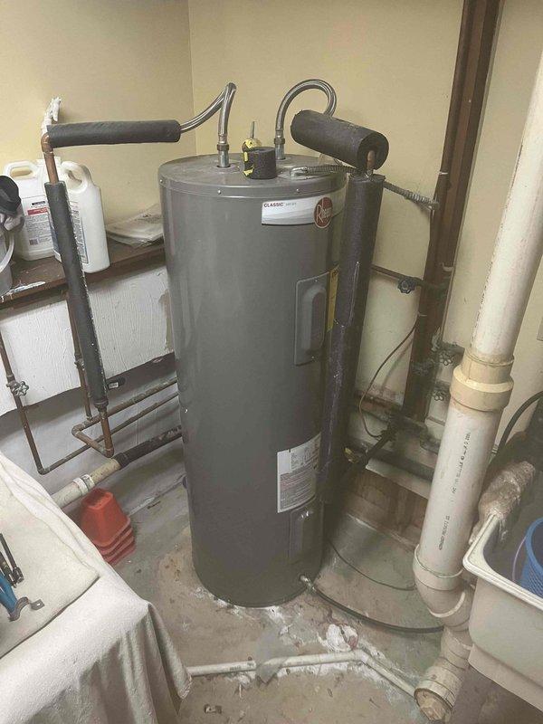 Completed residential tanked water heater installation with full copper piping system integration. Installed State brand water heater unit with proper expansion tank mounting, flexible connector hose, and comprehensive shut-off valve configuration throughout the copper pipe network. Exercised extra care during installation to protect newly refinished flooring in the work area, ensuring clean and professional completion of all plumbing connections and safety components.