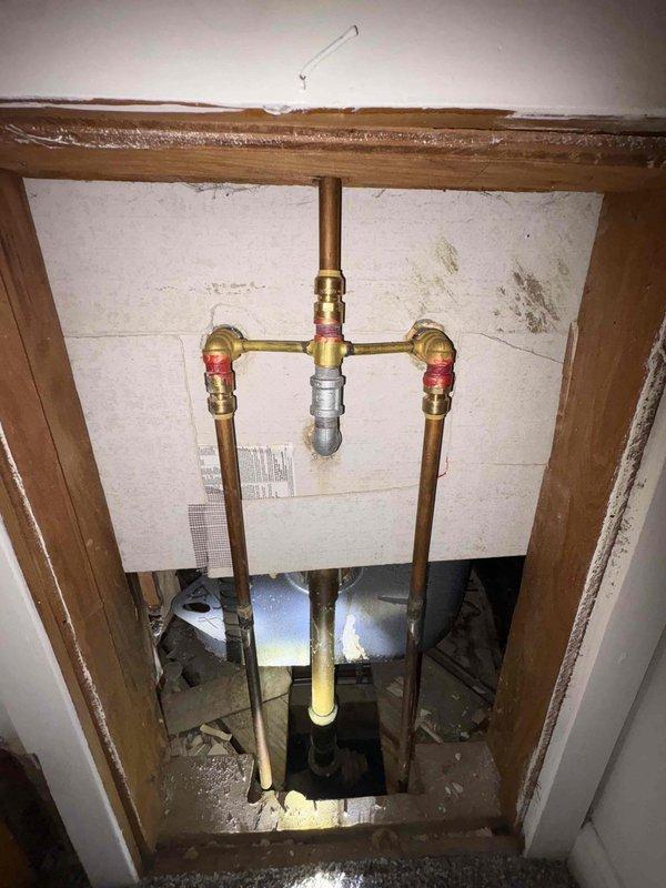 Responded to water leak complaint originating from bathtub drain system with active leaking into basement ceiling area. Upon inspection, identified compromised drain pipe with visible corrosion and rust perforation in vertical drain line. Documented existing plumbing configuration including copper supply lines with shut-off valves and deteriorated drainage piping requiring replacement. Photographed affected areas showing extent of rust damage and leak source for home warranty company documentation and approval for necessary repairs.