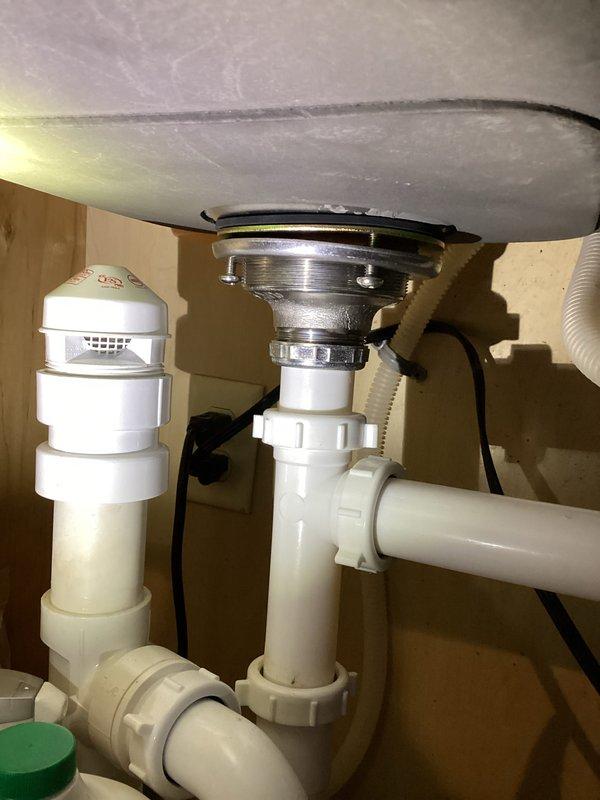 Completed plumbing membership inspection visit including comprehensive evaluation of under-sink drainage system and water heater equipment. Inspected kitchen/bathroom sink drain assembly, P-trap configuration, PVC piping connections, and air gap device, confirming all components are properly installed and functioning without visible leaks or deterioration. Documented water heater installation with dual anode rod protection system, verified contractor installation label and equipment specifications, and confirmed unit is operating within normal parameters.