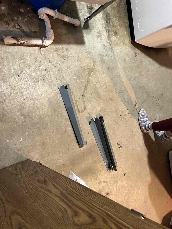 Responded to emergency call for utility sink collapse and major water leak causing flooding in basement area. Upon arrival, found white porcelain utility sink had detached from wall mounting, resulting in active water discharge onto concrete floor. Immediately shut off water supply to prevent further flooding damage.

Assessed structural damage to sink mounting system and determined cabinet support beneath sink had failed. Removed compromised sink assembly and inspected wall-mounted plumbing connections. Found copper supply lines and drainage system intact but required reconnection. Cleared standing water from work area and prepared surface for reinstallation.

Reinstalled utility sink with reinforced wall mounting brackets to ensure proper weight distribution and prevent future collapse. Secured cabinet base support structure and verified level positioning. Reconnected hot and cold water supply lines to chrome faucet assembly with pull-down spray head. Tested water pressure and inspec