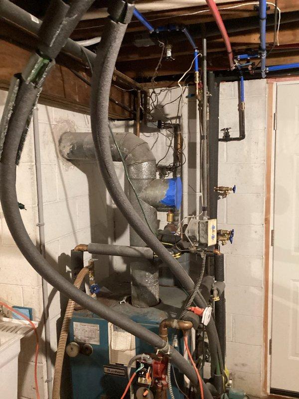 Evaluated existing oil-fired boiler system with supplementary wood fire boiler for potential conversion to propane fuel. Documented current installation including corroded electrical terminals and connections, mechanical components, and associated plumbing infrastructure in basement mechanical room to provide comprehensive estimate for fuel conversion project.