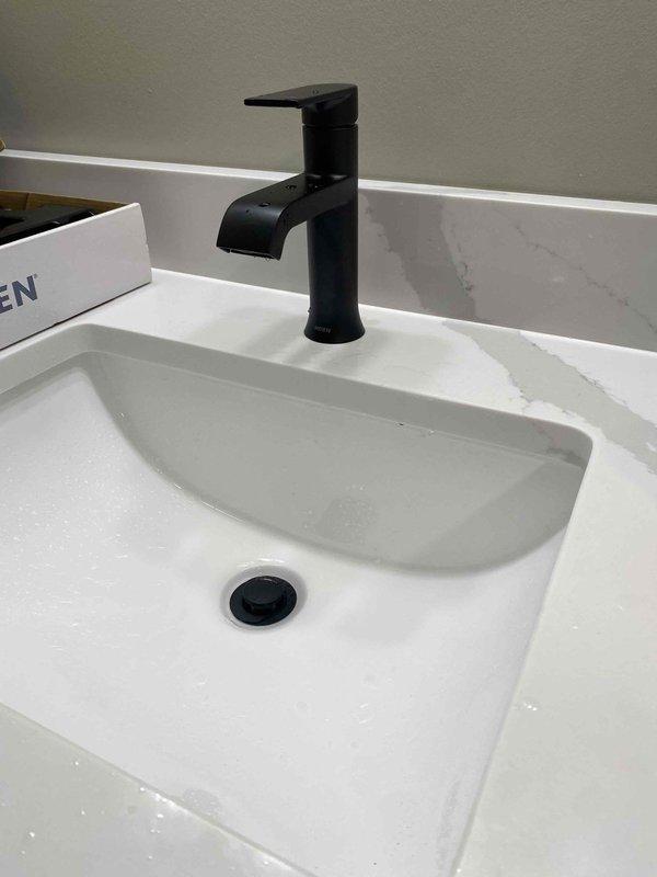 Returned to property to complete bathroom vanity sink installation. Successfully connected undermount white sink with matte black waterfall-style faucet and pop-up drain assembly to existing plumbing supply lines and drain system, ensuring all connections were secure and leak-free.
