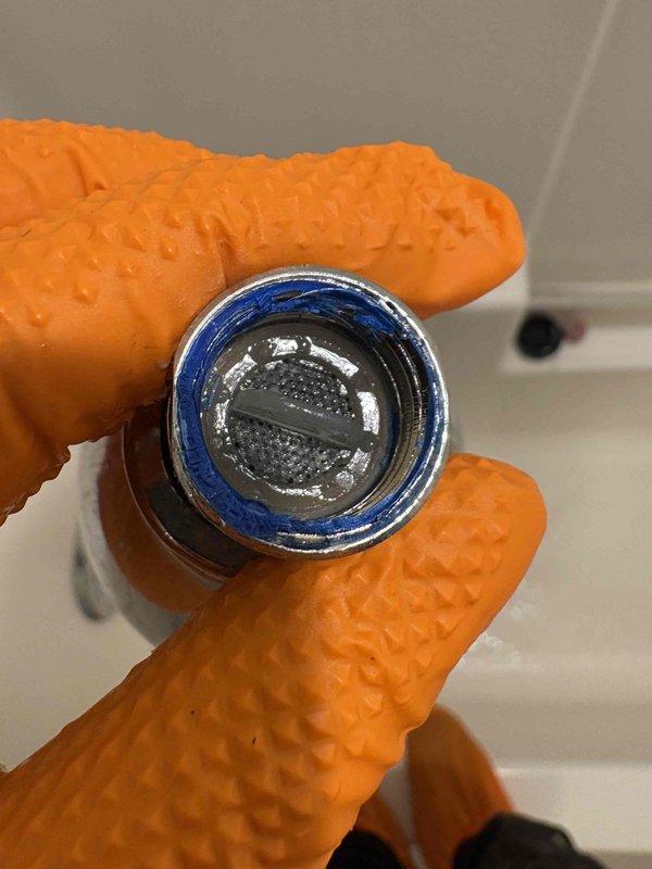 Responded to a reported water leak under the bathroom suspected to be originating from the sink. Upon inspection, identified and removed a faulty faucet aerator with a worn blue O-ring gasket that was causing water seepage. Replaced the defective component and verified proper installation to eliminate the leak.
