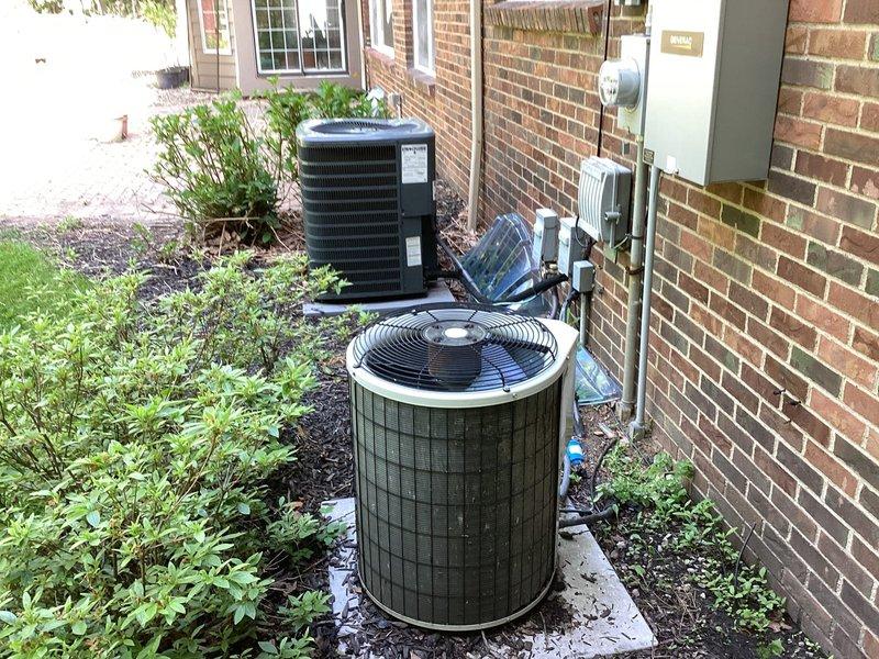 Completed HVAC estimate for replacement of dual-unit residential system including outdoor AC condenser units and indoor furnace equipment. The existing upstairs unit was found to have no refrigerant, and both aging systems required replacement evaluation. Documented current equipment conditions including weathered outdoor condensers positioned on concrete pads and basement furnace with exposed internal components for comprehensive replacement proposal.