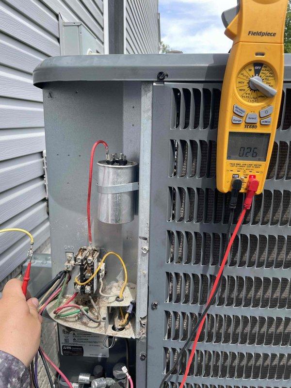 Responded to no cooling complaint with hissing noise from outdoor unit. Upon arrival, performed electrical diagnostics on condenser unit using multimeter to test capacitor and contactor operation. Capacitor tested at 66.87 microfarads and showed signs of failure with visible terminal corrosion. Replaced defective run capacitor, verified proper voltage and amperage readings across all electrical components, and confirmed system returned to normal operation with no abnormal sounds. Unit now cooling properly to thermostat set point.