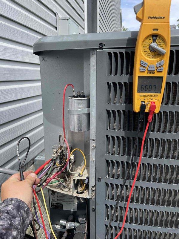 Responded to no cooling complaint with hissing noise from outdoor unit. Upon arrival, performed electrical diagnostics on condenser unit using multimeter to test capacitor and contactor operation. Capacitor tested at 66.87 microfarads and showed signs of failure with visible terminal corrosion. Replaced defective run capacitor, verified proper voltage and amperage readings across all electrical components, and confirmed system returned to normal operation with no abnormal sounds. Unit now cooling properly to thermostat set point.