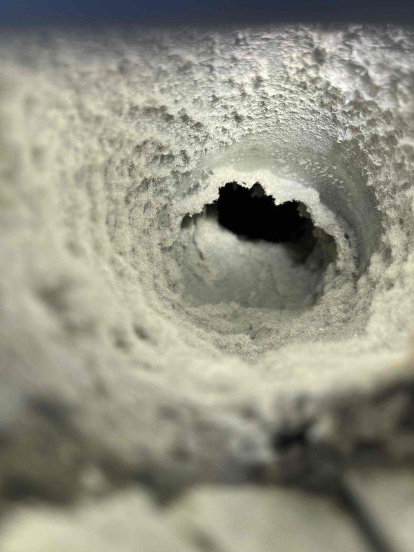 Responded to report of leaky ceiling in four-year-old residential property. Upon investigation, discovered the water intrusion was not plumbing-related but originated from HVAC system components. Inspected ductwork and ventilation system in affected area and found extensive accumulation of dust, lint, and debris throughout the duct interior and surrounding metal framework. The buildup was severe enough to potentially restrict airflow and cause condensation issues that could lead to moisture problems and ceiling damage. Documented conditions with photographic evidence showing thick, matted dust coating on metal surfaces and circular duct openings with crystalline-like debris accumulation along interior walls. Advised homeowner that the leak source requires HVAC specialist attention for proper duct cleaning, system inspection, and resolution of moisture issues rather than plumbing repair.