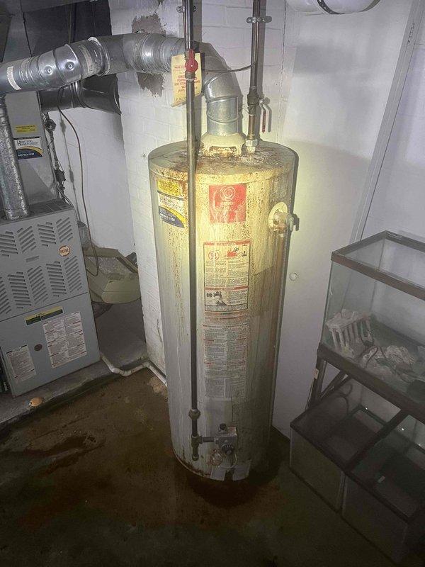 Responded to clogged kitchen sink at 50-year-old residential property. Upon arrival, performed initial assessment of plumbing system and drainage conditions. Inspected utility area and basement plumbing infrastructure to identify source of blockage and evaluate overall system condition.

During inspection, observed aging water heater with visible corrosion and rust accumulation at base, along with significant moisture damage and water staining on concrete floor throughout utility area. Floor exhibited yellowish-brown discoloration and dampness, indicating ongoing or recent water intrusion issues. Wall surfaces showed moisture exposure with staining near floor level, particularly in corner areas.

Cleared kitchen sink drain blockage using appropriate drain cleaning equipment and techniques. Verified proper water flow and drainage after clearing obstruction. Tested sink to ensure complete restoration of normal drainage function.

Documented existing conditions in utility area, including 