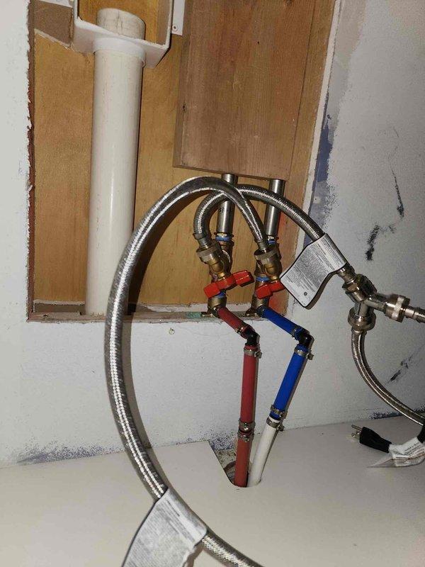 Responded to a hot water supply line leak at washing machine location. Upon inspection, identified active leak at connection point between hot water shut-off valve and braided flex supply hose serving the washing machine. Visible corrosion and mineral deposits were present on the affected valve and surrounding fittings, indicating long-term moisture exposure. Shut off water supply at fixture valves and removed compromised braided flex hose. Replaced defective hot water supply line with new stainless steel braided flexible connector, ensuring proper seal at both valve and appliance connections. Verified all connections were secure and leak-free. Restored water supply and tested system under full pressure to confirm repair integrity. Left work area clean with all connections functioning properly.