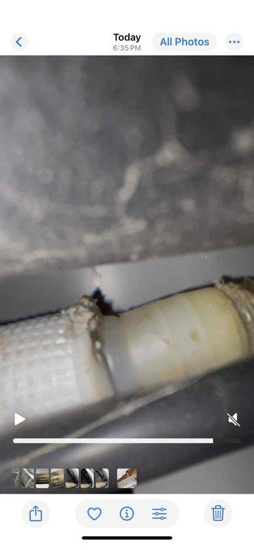 Responded to service call for mini split system experiencing continuous water leakage during AC operation. Upon inspection, identified improper drainage line connection and condensate discharge issues at the air handler unit. Inspected refrigerant line connections and condensate drain assembly, documenting conditions with photographs showing drain line coupling and flexible drain hose configuration in confined installation space.