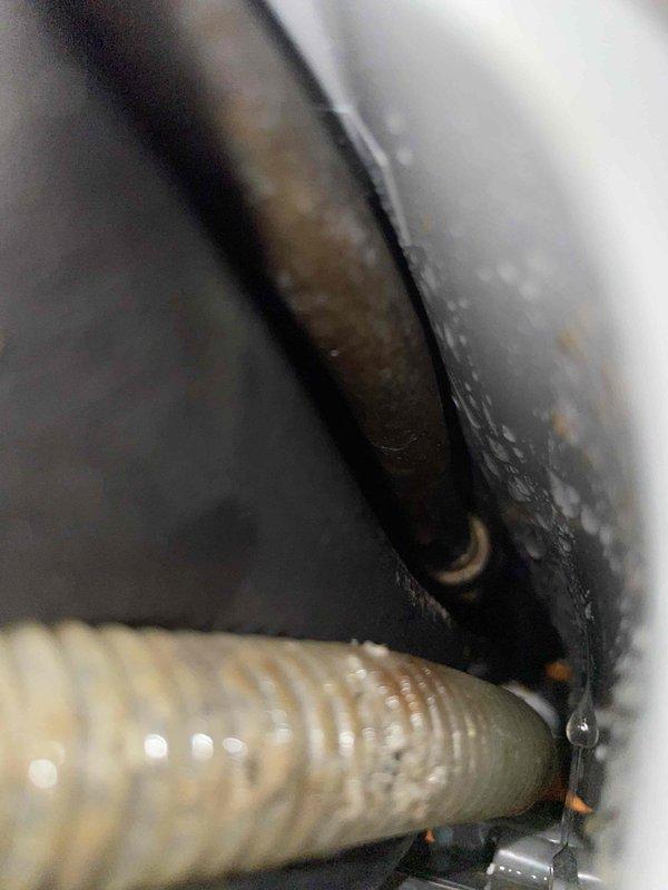 Responded to service call for mini split system experiencing continuous water leakage during AC operation. Upon inspection, identified improper drainage line connection and condensate discharge issues at the air handler unit. Inspected refrigerant line connections and condensate drain assembly, documenting conditions with photographs showing drain line coupling and flexible drain hose configuration in confined installation space.