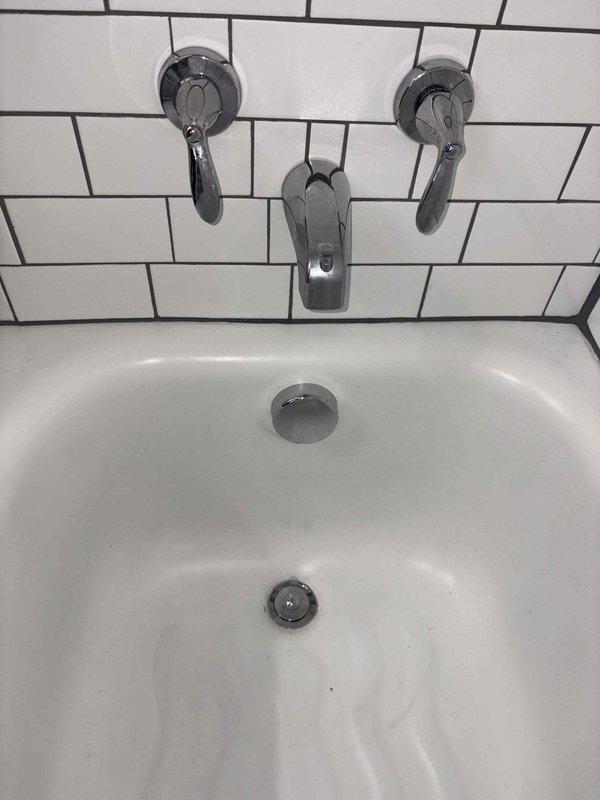 Completed return visit to replace bathtub waste and overflow assembly and update the tub trap configuration with proper tie-in to the existing horizontal drain line. Removed old tub drain components and installed new chrome overflow cover plate and drain stopper assembly. Updated trap piping beneath the tub with copper and brass fittings, ensuring proper venting and drainage flow to meet code requirements.