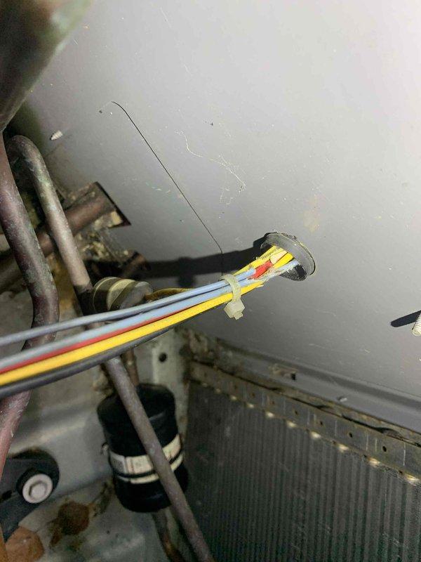 Responded to service call for air conditioning system not adequately cooling the property. Upon arrival, performed diagnostic inspection of the outdoor condensing unit and electrical connections. Observed exposed electrical wiring at the unit with multiple conductors entering through wall penetration, including proper color-coded wires routed into the equipment compartment. Inspected condenser coil, refrigerant lines, and electrical components for proper operation. Unit appeared to be functioning within normal parameters during inspection. Verified all electrical connections were secure and properly terminated. Recommended monitoring system performance and advised customer to contact for follow-up if cooling issues persist.
