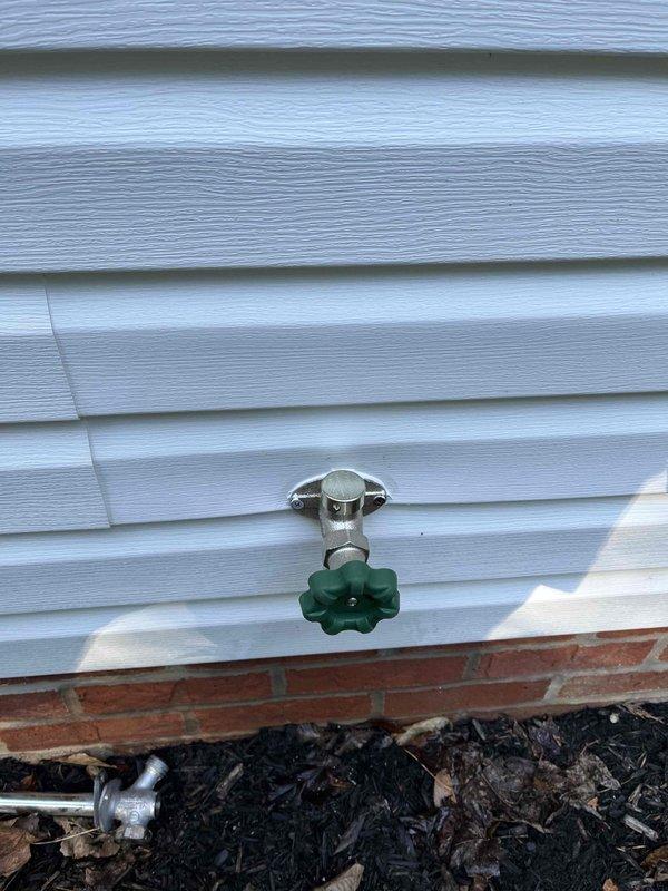 Installed two outdoor water spigots as part of a promotional service offering. Routed copper supply lines through interior wall framing, secured piping with appropriate hangers, and installed shut-off valves for seasonal maintenance. Mounted frost-free hose bibs on exterior white vinyl siding above brick foundation, ensuring proper drainage slope and weatherproof seal to prevent water intrusion.