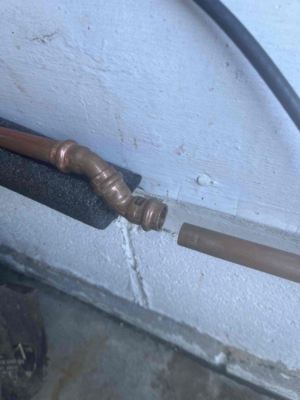 Responded to a burst pipe emergency at the front yard spigot of a 1950s-era home that had sustained freeze damage during winter conditions. The affected copper piping showed significant weathering and oxidation consistent with the age of the property and had been subject to previous repair attempts. Accessed the plumbing system through the basement utility area where horizontal copper supply lines were mounted along concrete block walls. Assessed the compromised pipe section and associated fittings, which displayed advanced patina and age-related deterioration. Replaced the damaged copper elbow fitting and adjacent pipe sections to restore water supply integrity to the exterior spigot. Secured all new copper connections with proper soldering techniques and verified system pressure upon restoration of water flow. Confirmed no additional leaks were present at the repair site or surrounding plumbing infrastructure.