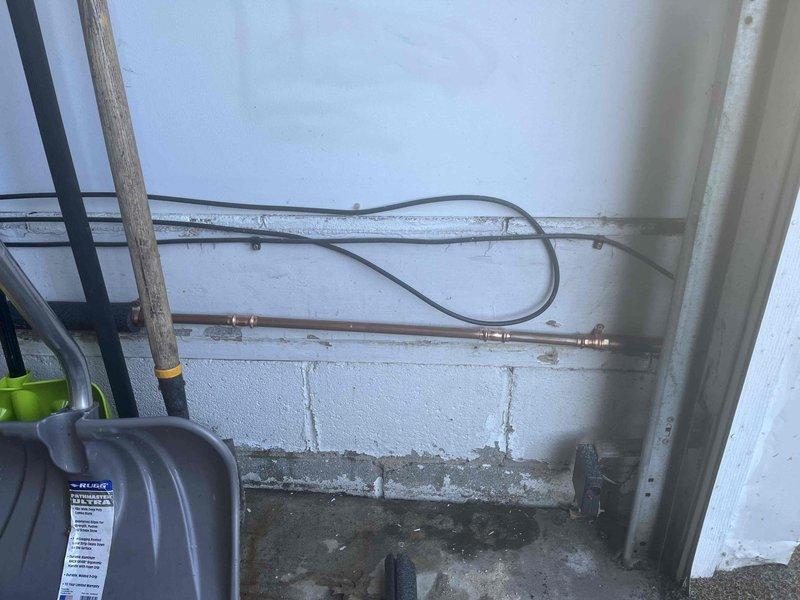 Responded to a burst pipe emergency at the front yard spigot of a 1950s-era home that had sustained freeze damage during winter conditions. The affected copper piping showed significant weathering and oxidation consistent with the age of the property and had been subject to previous repair attempts. Accessed the plumbing system through the basement utility area where horizontal copper supply lines were mounted along concrete block walls. Assessed the compromised pipe section and associated fittings, which displayed advanced patina and age-related deterioration. Replaced the damaged copper elbow fitting and adjacent pipe sections to restore water supply integrity to the exterior spigot. Secured all new copper connections with proper soldering techniques and verified system pressure upon restoration of water flow. Confirmed no additional leaks were present at the repair site or surrounding plumbing infrastructure.