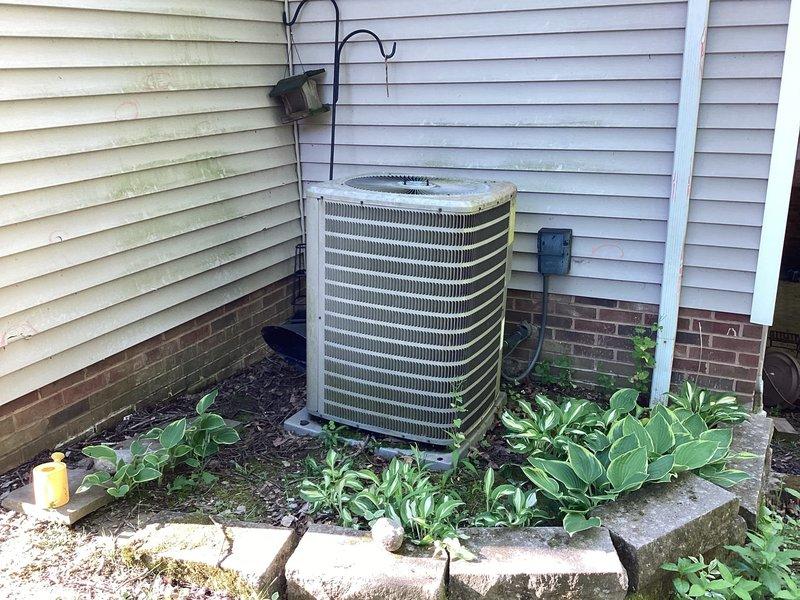 Conducted comprehensive assessment of existing 20-year-old residential air conditioning system that sustained hail damage to outdoor condensing unit. Documented current equipment condition through detailed photographic evidence, including interior control board components and exterior unit placement. System evaluated for insurance claim purposes with installation scheduled approximately 6 months from assessment date. Inspected control board assembly, wiring harness connections, terminal blocks, and electronic modules within unit housing. Exterior condensing unit examined showing horizontal fin configuration positioned on concrete pad against residence foundation with surrounding landscaping. Provided complete documentation and equipment specifications for HVAC replacement estimate to support insurance claim process.