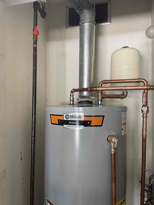 Responded to no hot water complaint and investigated plumbing configuration. Discovered hot water line was incorrectly connected to old heating system lines, preventing proper hot water distribution throughout the residence. Identified residual water remaining in pipes that should have been flushed during previous installation. Documented existing State ProLine water heater installation with copper piping, expansion tank, pressure relief valves, and proper venting system for service records and future corrective action.