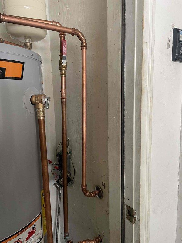 Responded to no hot water complaint and investigated plumbing configuration. Discovered hot water line was incorrectly connected to old heating system lines, preventing proper hot water distribution throughout the residence. Identified residual water remaining in pipes that should have been flushed during previous installation. Documented existing State ProLine water heater installation with copper piping, expansion tank, pressure relief valves, and proper venting system for service records and future corrective action.