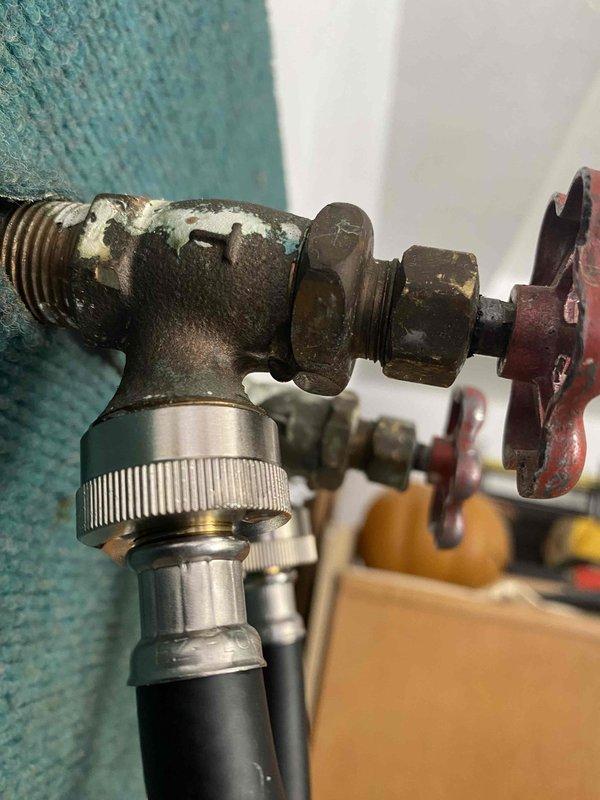 Installed new hot and cold water shut-off valves with hose connection capability in garage to replace heavily corroded existing plumbing assembly. Customer now has functional outdoor spigot system with proper threaded hose bib connections for standard garden hose attachment.