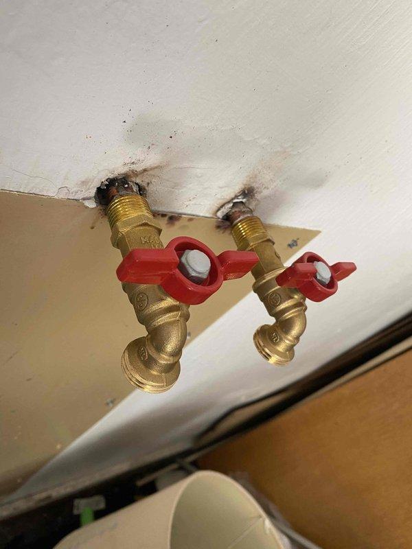 Installed new hot and cold water shut-off valves with hose connection capability in garage to replace heavily corroded existing plumbing assembly. Customer now has functional outdoor spigot system with proper threaded hose bib connections for standard garden hose attachment.
