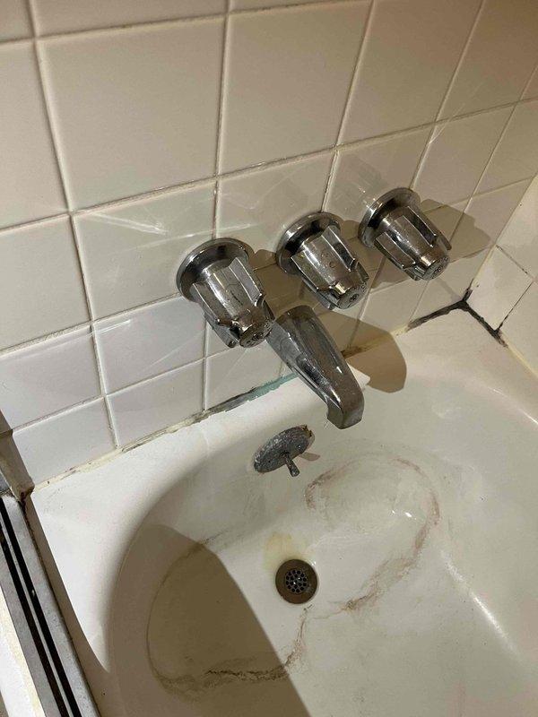 Responded to service call for non-functioning garbage disposal and leaking upstairs bathtub faucet in residential property being prepared for sale. Inspected kitchen garbage disposal unit and diagnosed electrical or mechanical failure requiring replacement or repair. Evaluated upstairs bathroom three-handle chrome faucet fixture and identified active leak requiring washer replacement or cartridge service. Documented existing bathroom conditions including aged tile grout, fixture wear, and tub surface staining for customer records prior to property listing.