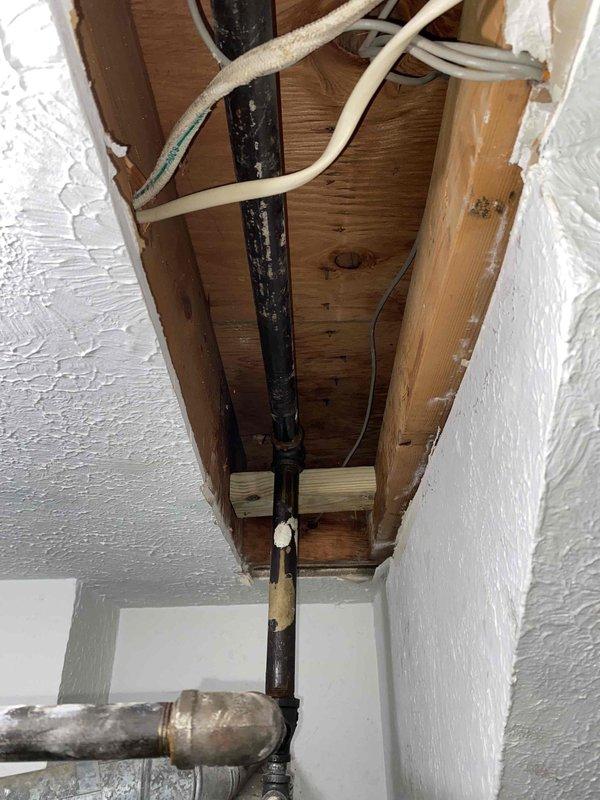 Returned to property to provide support for main gas line system and complete necessary repiping work as previously sold. Accessed utility area in basement where existing HVAC equipment, water heater, and gas distribution components are located. Removed section of ceiling drywall to expose concealed piping runs and wooden joists for proper access to gas line routing. Installed new black iron gas piping through ceiling cavity, ensuring proper sizing and support per code requirements. Made necessary connections to existing gas distribution system, including work at galvanized fittings and integration points with current infrastructure. Verified all joints and connections for proper fit and alignment. Work performed in coordination with scheduled moving pod arrival to minimize disruption. All installations completed following applicable gas piping standards and building codes for safe operation of heating equipment and gas-fired appliances.