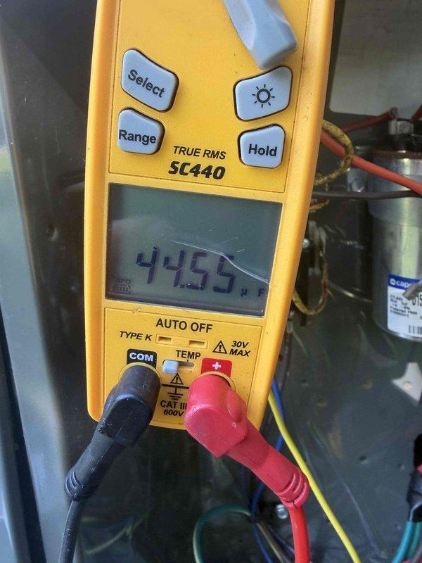 Completed comprehensive AC tune-up service including system diagnostics and performance verification. Inspected and tested electrical components with digital multimeter, recording voltage reading of 445.8V at capacitor terminals. Evaluated and replaced heavily soiled air filter showing significant dust accumulation and discoloration. Additionally performed water heater flush service as requested to remove sediment buildup and maintain optimal unit performance.