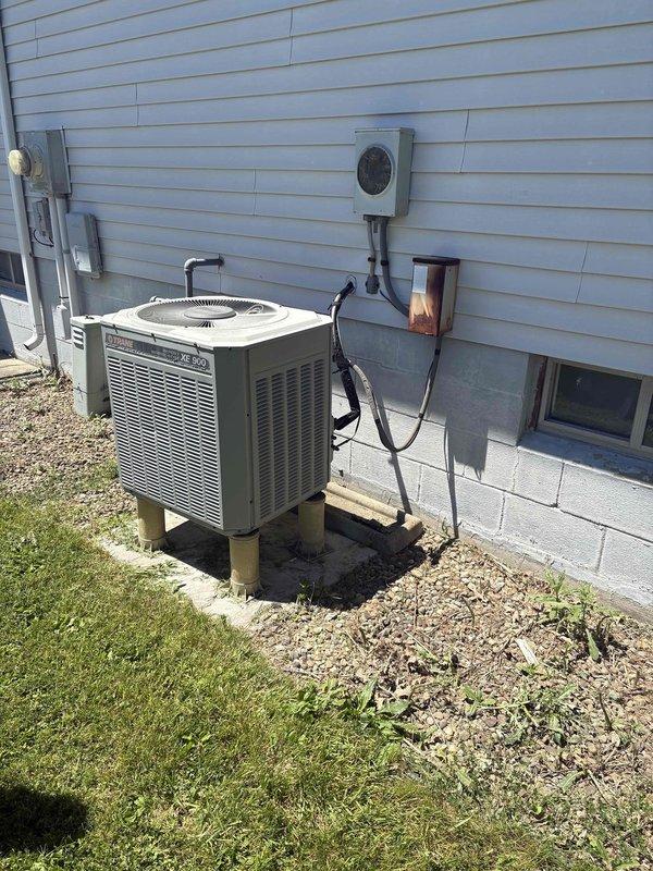 Conducted comprehensive assessment of existing residential HVAC system for replacement estimate. System consists of Trane XR 70 furnace located in basement utility area and corresponding outdoor air conditioning unit mounted on concrete blocks adjacent to building exterior. Documented current equipment configuration including ductwork connections, electrical disconnect, refrigerant lines, and condensate drainage system. Captured detailed photographic documentation of both indoor and outdoor units to support replacement options and equipment specifications.
