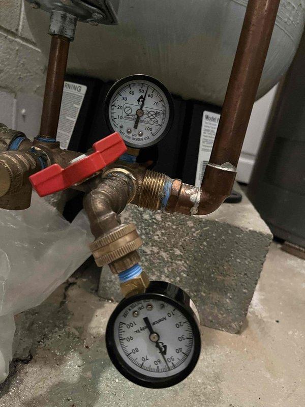 Responded to customer concerns regarding reduced water pressure during simultaneous fixture use and clicking sounds from the pressure tank. Performed diagnostic testing of the well water system, including pressure gauge readings which confirmed system pressure at 35 PSI. Inspected the pressure tank installation, copper piping connections, pressure relief valves, and associated plumbing components for proper operation and potential issues affecting water pressure delivery throughout the residence.