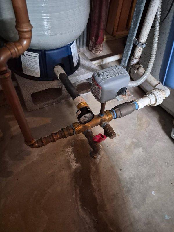 Responded to water leak complaint and inspected plumbing manifold assembly beneath water heater system. Found brass manifold fitting with visible crack causing active leak onto concrete floor. Replaced damaged manifold component and associated fittings, ensuring proper seal on all copper pipe connections. Tested system under full pressure to verify leak repair was successful with no further water discharge observed.