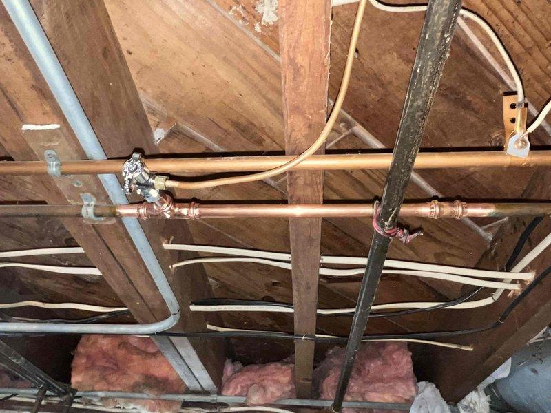 Responded to water leak complaint originating from wall when main water supply was activated. Investigated attic and ceiling space plumbing infrastructure, inspecting copper supply lines, brass fittings, valves, and associated piping systems within the overhead structural framework. Identified leak source in water distribution system. Coordinated findings with dispatch for further action and repair authorization.