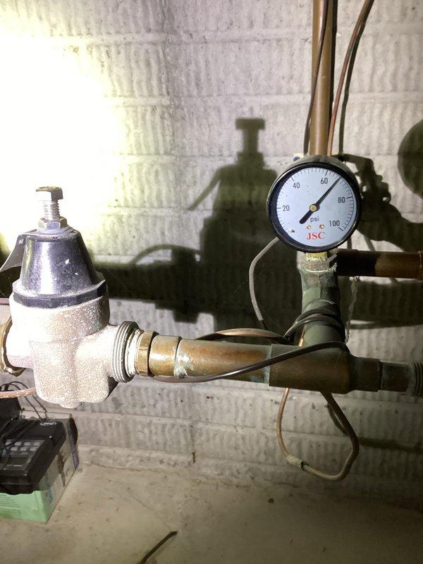 Responded to water leak complaint in basement bathroom with moisture detected around baseboards and carpet. Conducted thorough inspection of plumbing systems including pressure reducing valve assembly and under-sink plumbing connections. Documented existing plumbing infrastructure with photographic evidence showing pressure gauge readings and disposal unit configuration for diagnostic purposes and future reference.