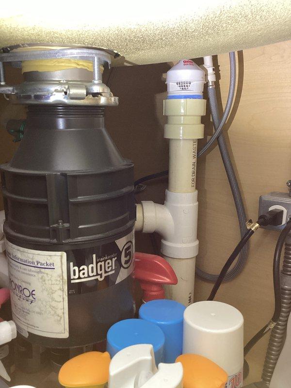 Responded to water leak complaint in basement bathroom with moisture detected around baseboards and carpet. Conducted thorough inspection of plumbing systems including pressure reducing valve assembly and under-sink plumbing connections. Documented existing plumbing infrastructure with photographic evidence showing pressure gauge readings and disposal unit configuration for diagnostic purposes and future reference.