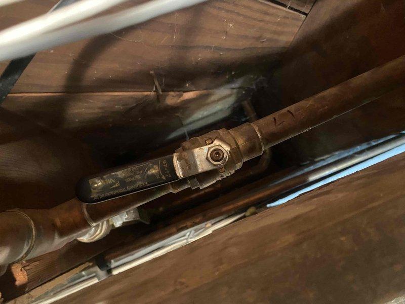 Responded to service call for leaking valve on boiler system. Upon inspection, identified compromised valve connection on copper piping with visible moisture and deterioration at joint. Documented condition with photos and video showing valve assembly beneath flooring area with evidence of active leak at connection point.
