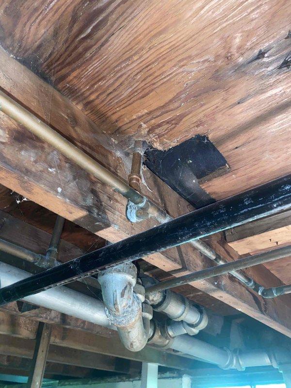 Responded to address multiple plumbing concerns in bathroom with water damage from previous leak. Permanently repaired temporary copper hot water pipe fix that had been improperly addressed. Installed customer-supplied lavatory faucet and shower valve, adding two new shutoff valves to isolate bathroom plumbing system during shower valve installation. Work required accessing basement ceiling area where copper and PVC supply lines were visible among exposed wooden beams showing moisture damage. Bathroom walls exhibited significant deterioration and water staining around tub surround, indicating extent of previous leak damage. All installations completed using stock materials with proper isolation valves for future maintenance accessibility.