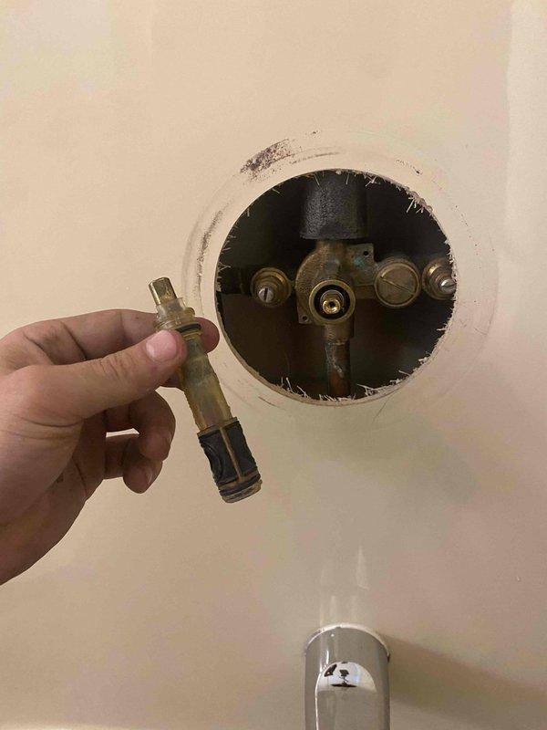 Returned to property to complete installation of new shower cartridge and pressure reducing valve (PRV) as previously sold. Accessed shower valve assembly through existing wall opening, removed old worn cartridge showing mineral deposits and corrosion, and installed replacement cartridge. Inspected PRV and associated plumbing connections in water heater compartment, verified proper operation of gas valve assembly and copper piping connections. All components tested and functioning properly upon completion.