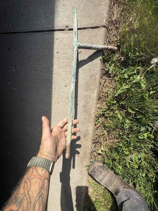 Returned to property to complete follow-up work on previously sold plumbing repair. Conducted thorough inspection of outdoor water service line area along concrete curb and property perimeter. Located and identified corroded metal stake marking the main water line shut-off valve position. Documented existing conditions showing significant oxidation and deterioration of the marker stake, which had developed green patina and rust damage affecting its visibility and structural integrity. Cleared vegetation and debris from the curb line to improve access to the water service area for future maintenance needs. Verified proper location of underground utilities and ensured all markers remained visible for emergency shut-off access.