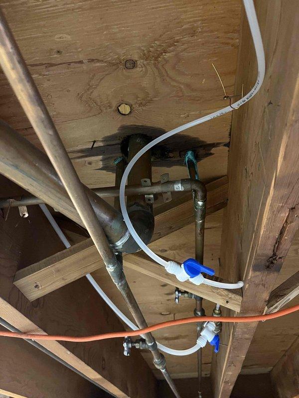Responded to a water leak originating from the first floor bathroom. Upon inspection, accessed the area below through the basement/crawlspace and located the source of the leak in the plumbing supply lines. Installed a new shut-off valve with blue lever handle on the white PEX supply line to isolate the affected section and prevent future leaks. Secured all plumbing lines properly to the wooden floor joists and verified all connections were tight and leak-free before completing the repair.