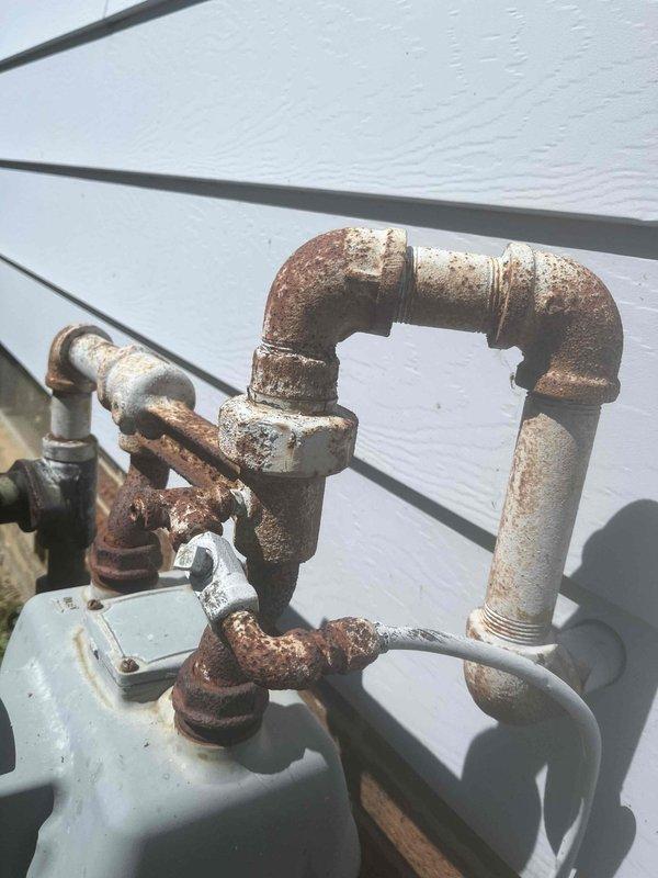 Responded to gas line service call for fallen lamp post. Successfully capped the gas supply line feeding the exterior lamp post fixture and removed the damaged post assembly that had fallen over. The existing gas piping system showed extensive rust and corrosion throughout the assembly, including the shut-off valve, elbow fittings, and threaded connections mounted on the exterior wall. Safely isolated and terminated the gas line to eliminate potential leak hazard from the compromised fixture.