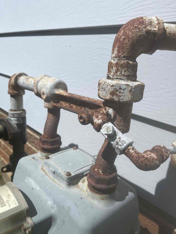 Responded to gas line service call for fallen lamp post. Successfully capped the gas supply line feeding the exterior lamp post fixture and removed the damaged post assembly that had fallen over. The existing gas piping system showed extensive rust and corrosion throughout the assembly, including the shut-off valve, elbow fittings, and threaded connections mounted on the exterior wall. Safely isolated and terminated the gas line to eliminate potential leak hazard from the compromised fixture.