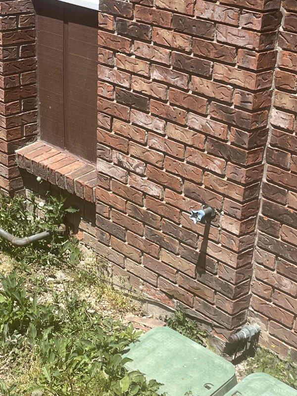 Performed follow-up service on outdoor spigot installation where wall access had been previously opened. Accessed plumbing through existing interior wall opening to complete connection work on exterior hose bib mounted on brick facade. Verified proper installation and operation of outdoor faucet fixture.