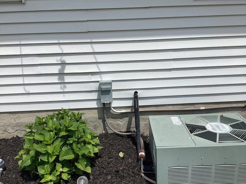 Completed comprehensive estimate for full HVAC system replacement on 25-year-old furnace and air conditioning unit. Assessed existing downdraft furnace and failing AC unit that required refrigerant recharge previous season and is no longer operating correctly. Provided replacement quote for 80% efficiency two-stage downdraft furnace paired with 2.5-ton 13.4 SEER R32 air conditioning unit with matching evaporator coil. Evaluated installation requirements including new refrigerant line set from outdoor condenser to indoor air handler. Documented existing gray metal ductwork and air handler installation in interior mechanical space, photographed current outdoor AC unit positioned on concrete pad against vinyl siding with electrical disconnect and conduit connections. Discussed equipment options, system sizing requirements, and financing alternatives for complete system replacement.