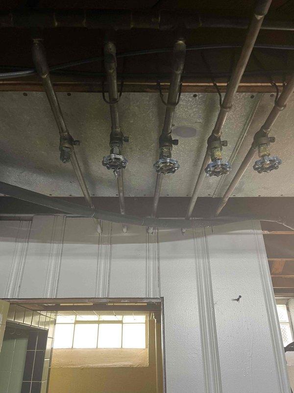 Responded to emergency plumbing call at 75-year-old residential property to address malfunctioning shut-off valve in basement utility area. Inspected water distribution manifold system consisting of five parallel supply lines with brass ball valves featuring red control handles. Identified faulty valve mechanism causing inadequate water flow control, replaced defective valve assembly with new brass ball valve, tested all zone control valves for proper operation, and verified system integrity with no leaks detected upon restoration of water pressure.