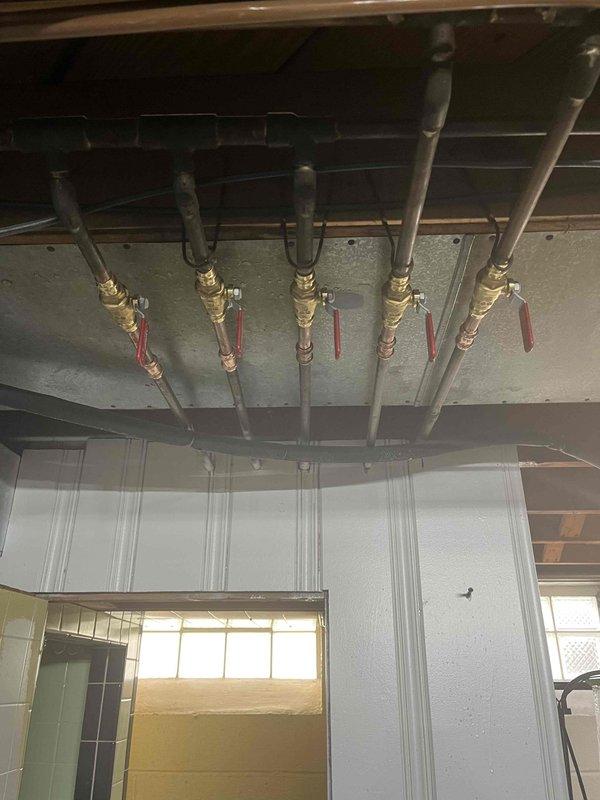 Responded to emergency plumbing call at 75-year-old residential property to address malfunctioning shut-off valve in basement utility area. Inspected water distribution manifold system consisting of five parallel supply lines with brass ball valves featuring red control handles. Identified faulty valve mechanism causing inadequate water flow control, replaced defective valve assembly with new brass ball valve, tested all zone control valves for proper operation, and verified system integrity with no leaks detected upon restoration of water pressure.