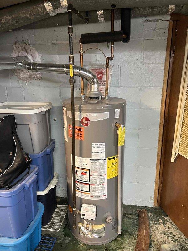 Responded to service call for small leak at bottom of tanked water heater in 70-year-old residential property. Upon inspection, identified moisture accumulation at base of Rheem water heater unit located in basement utility area. Assessed all visible plumbing connections, including copper supply lines and discharge piping, for signs of active leakage or corrosion. Examined temperature and pressure relief valve, drain valve, and tank integrity. Documented existing conditions including concrete floor staining consistent with previous moisture exposure. Photographed water heater installation, surrounding plumbing infrastructure, and exterior foundation areas including basement window wells for comprehensive service records.