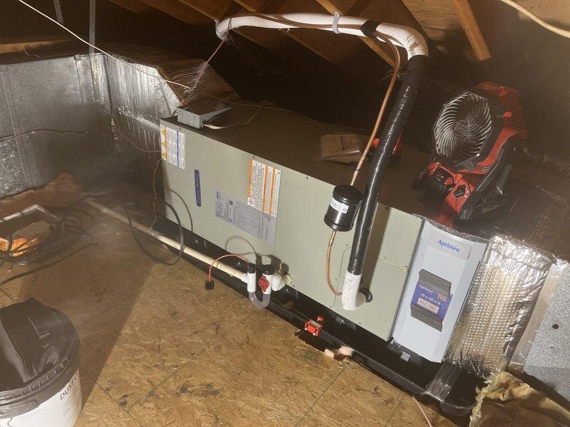 Completed installation of new air conditioning system and evaporator coil in attic space. Installed air handler unit with proper refrigerant line connections, condensate drain piping with PVC fittings, and flexible ductwork. Verified system operation and temperature readings using digital thermometer to ensure proper cooling performance and airflow throughout the system.